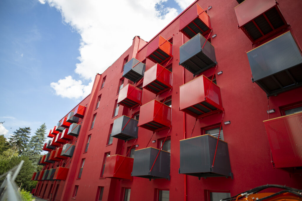 Rotes Wohngebäude mit kleinen Balkons in Rot und schwarz