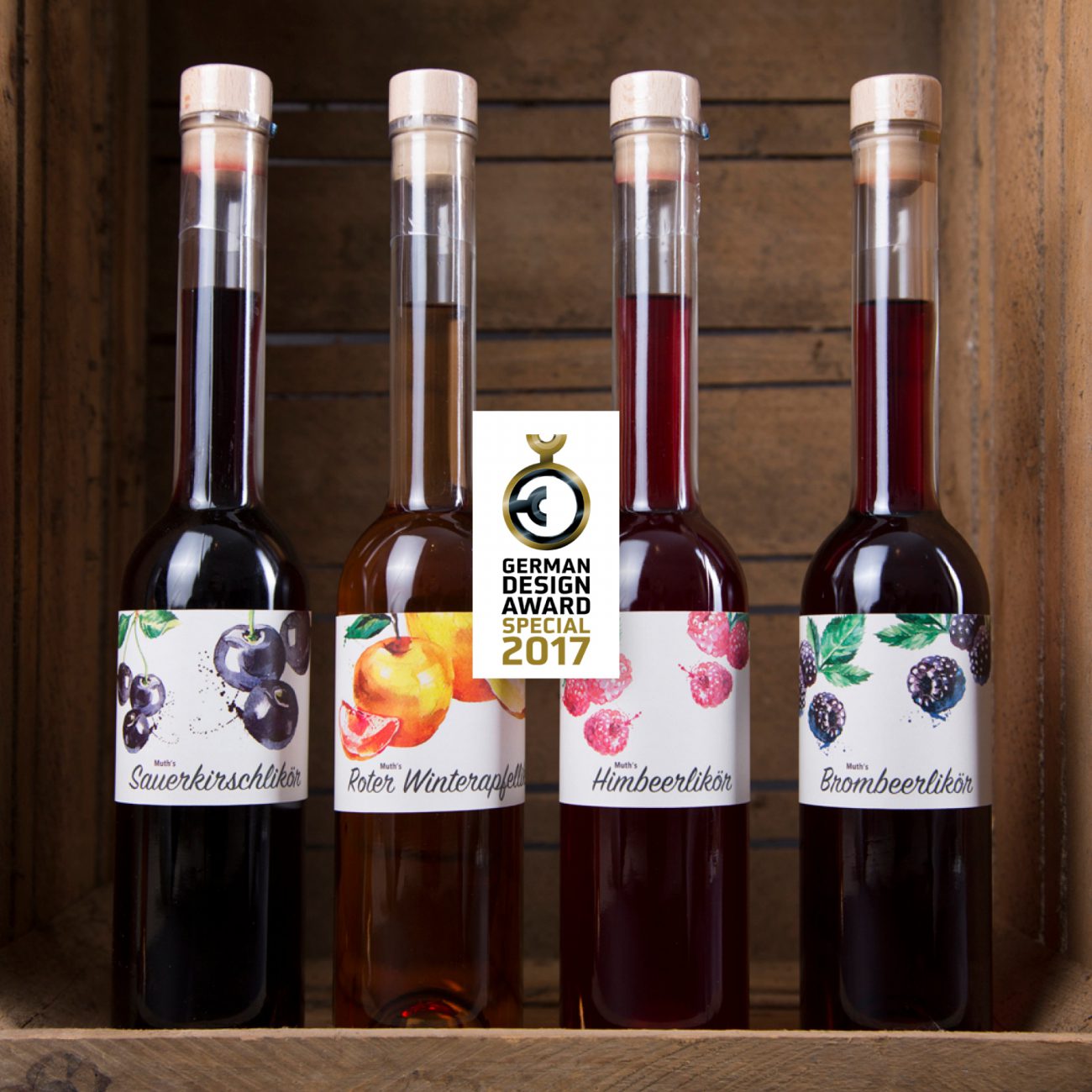 Vier Likörflaschen in einer Holzkiste und dem Logo des German Design Awards 2017, verschiedene Likörsorten