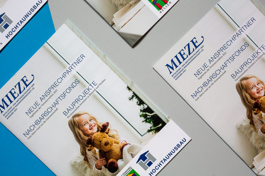 Titelbild der MIEZE auf einem blauen und hellgrauen Hintergrund, mehrere Zeitschriften zu sehen, auf dem Titel ein kleines Mädchen mit Elch-Kuscheltier